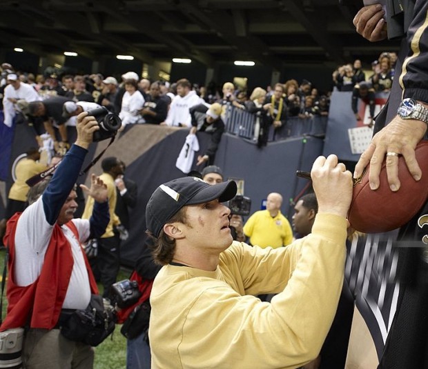 NOS Quarterback Drew Brews signing his autograph on a football of a fan