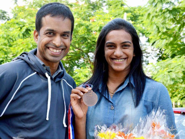 Sindhu showing her world championship medal along with her coach Gopichand